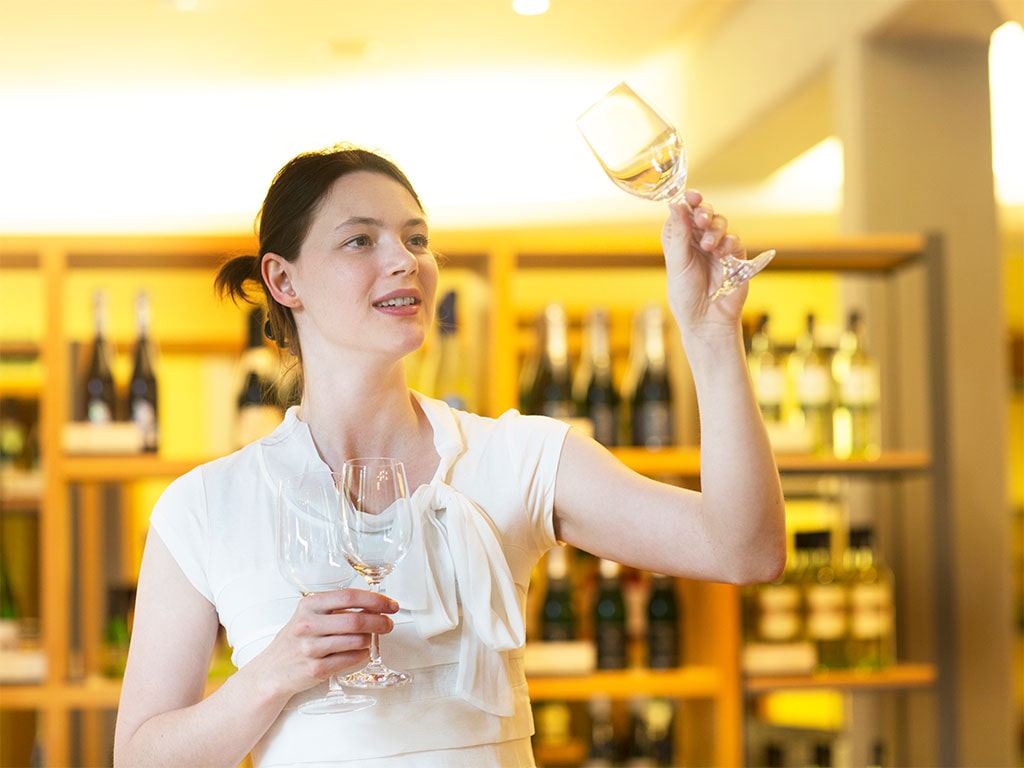 Woman inspecting glass of white wine.